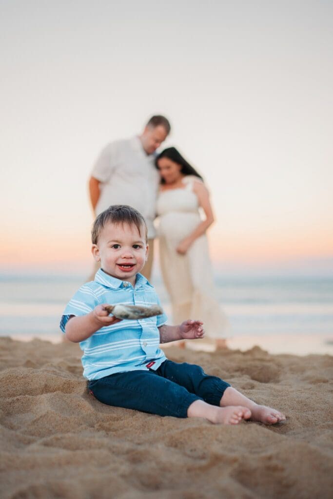 Dad holding toddler in the air with sunset light behind them at Salisbury Beach MA